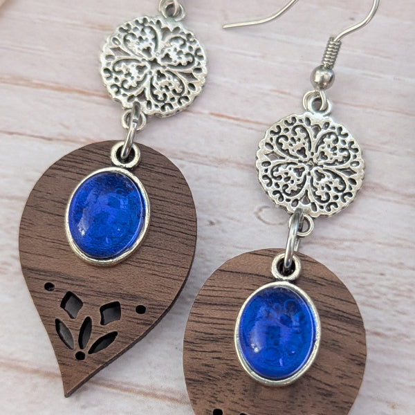 Pair of earrings with wooden and metal designs on a light wood surface