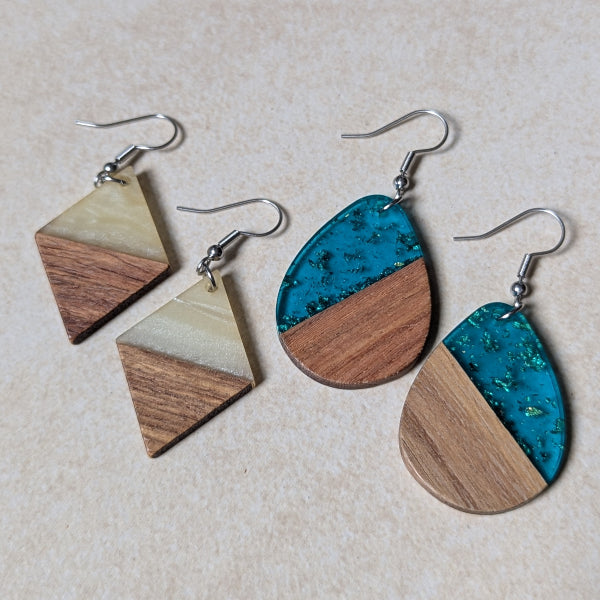 Two pairs of colourful earrings made from resin and wood on a beige background. Stainless steel hooks.