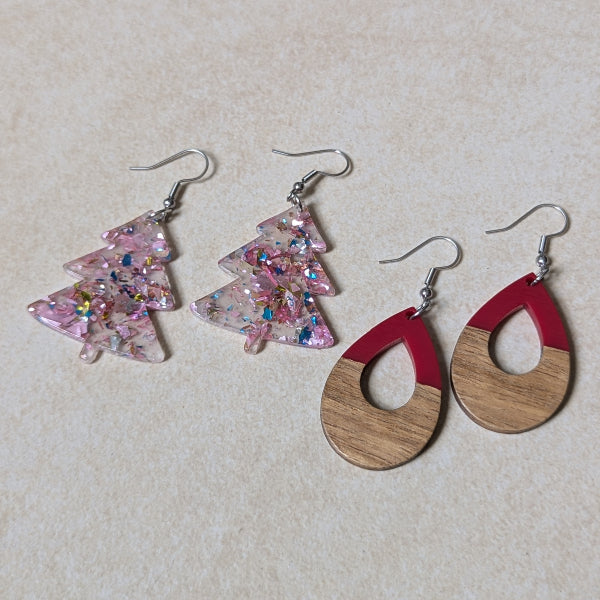 Two pairs of colourful earrings made from resin and wood on a beige background. Stainless steel hooks.