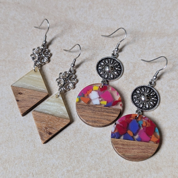 Two pairs of colourful earrings made from resin and wood on a beige background. Stainless steel hooks.