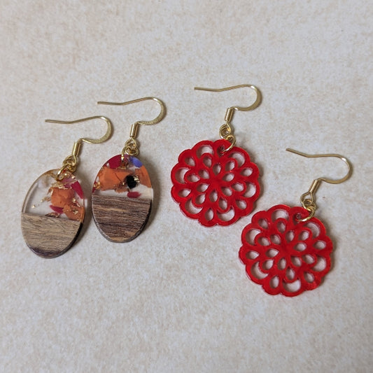Two pairs of colourful earrings made from resin and wood on a beige background. Plated gold hooks.