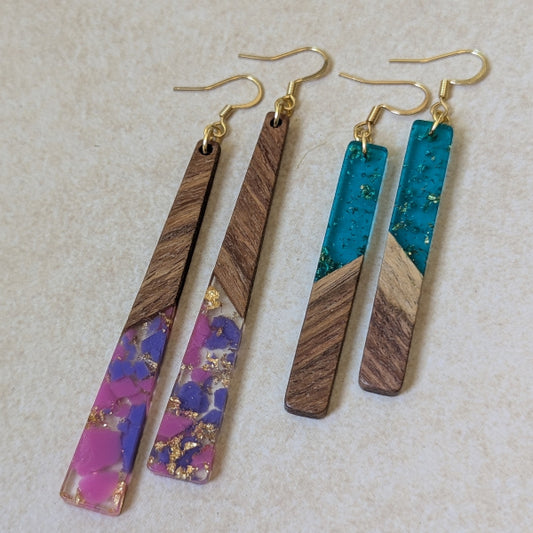 Two pairs of colourful earrings made from resin and wood on a beige background. Plated gold hooks.