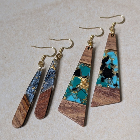 Two pairs of colourful earrings made from resin and wood on a beige background. Plated gold hooks.