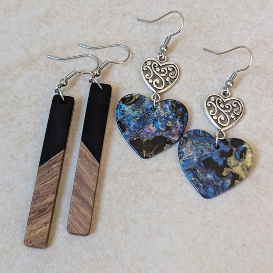 Two pairs of resin and wood earrings on a textured beige surface.
