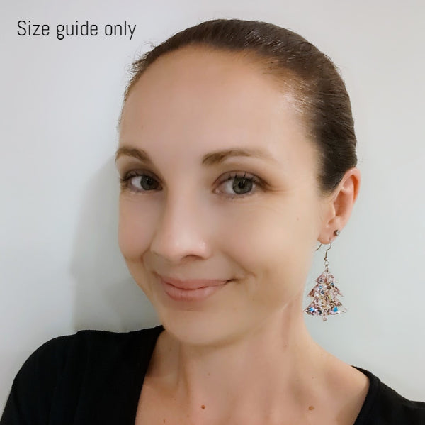 Women wearing pink Christmas earrings as a size guide.