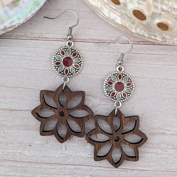 Wooden floral earrings with red and silver circular accents on a light wooden surface.
