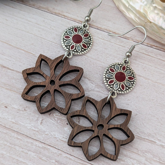 Wooden floral earrings with silver and red embellishments on a light wooden surface