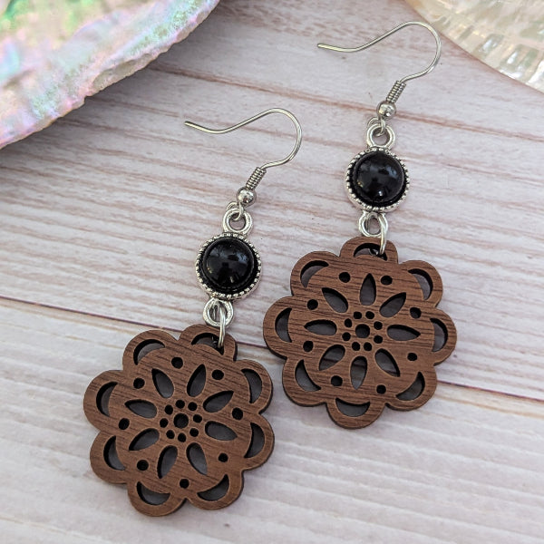 Wooden floral earrings with black connectors on a wooden surface