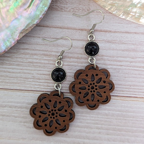 Wooden floral earrings with black connectors on a wooden surface