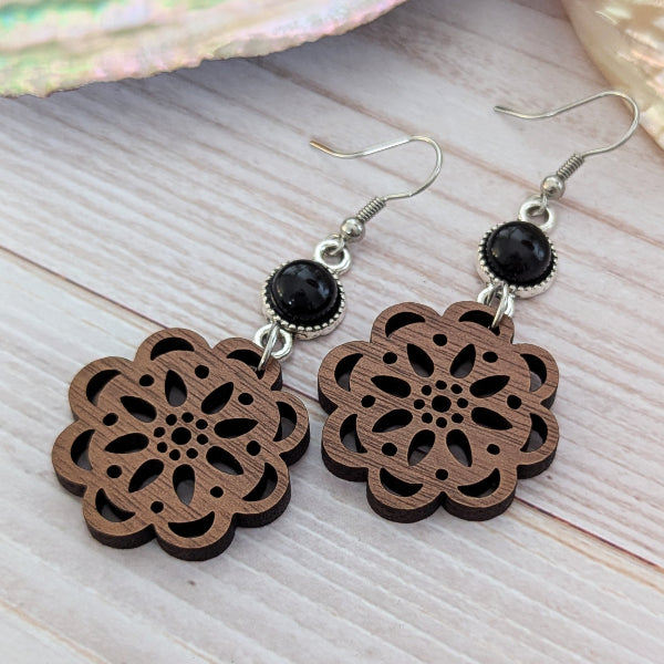 Wooden floral earrings with black connectors on a wooden surface