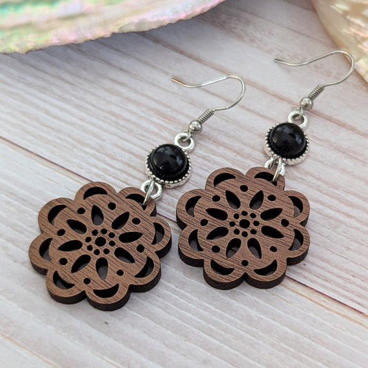 Wooden floral earrings with black connectors on a wooden surface