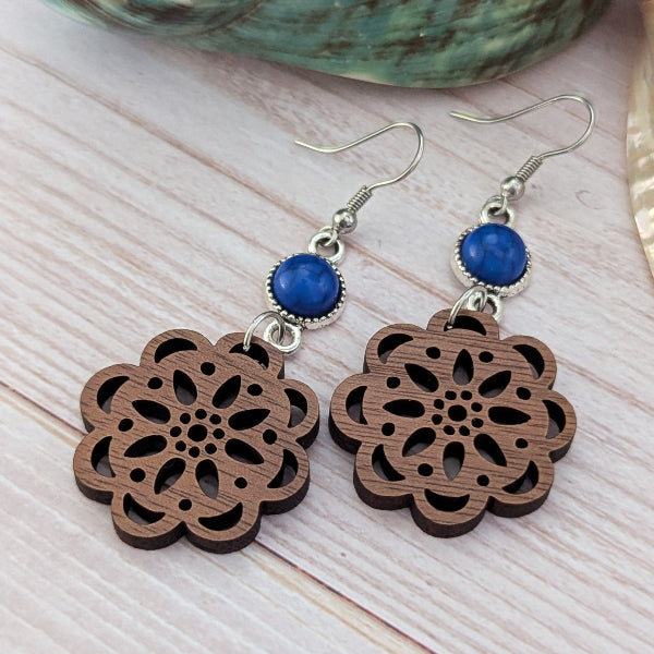 Wooden floral earrings with blue stones on a wooden surface