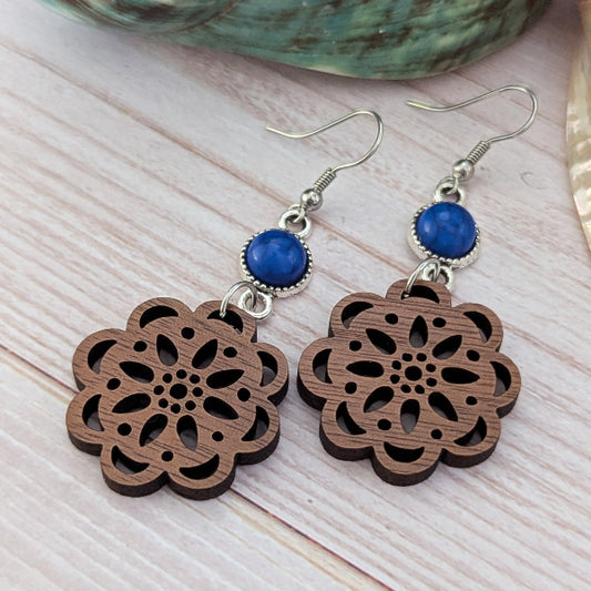 Wooden floral earrings with blue stones on a wooden surface