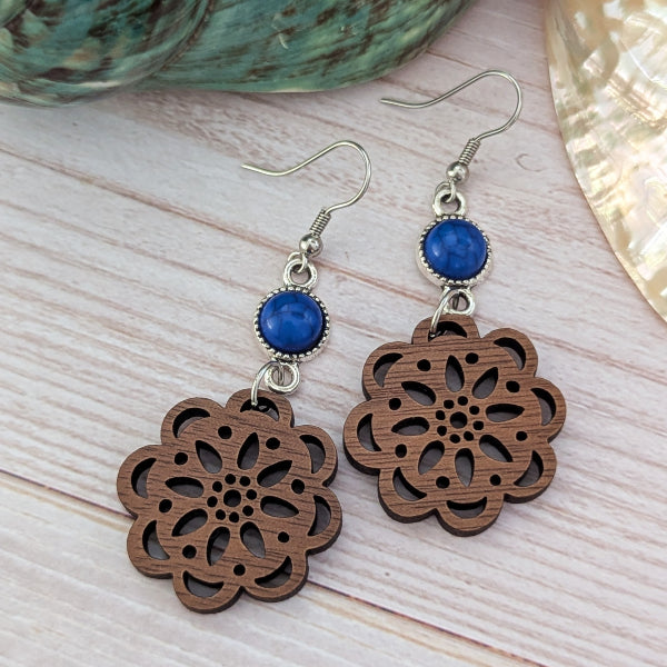 Wooden floral earrings with blue stones on a wooden surface
