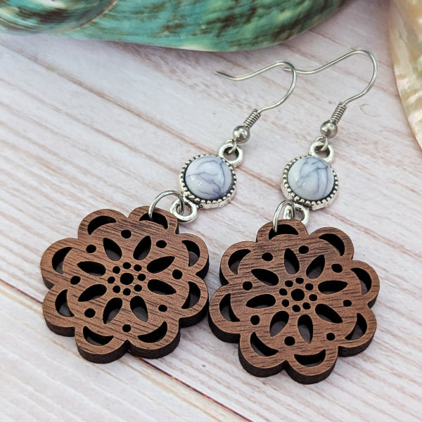 Wooden floral earrings with silver hooks and marbled stones on a light wooden surface.