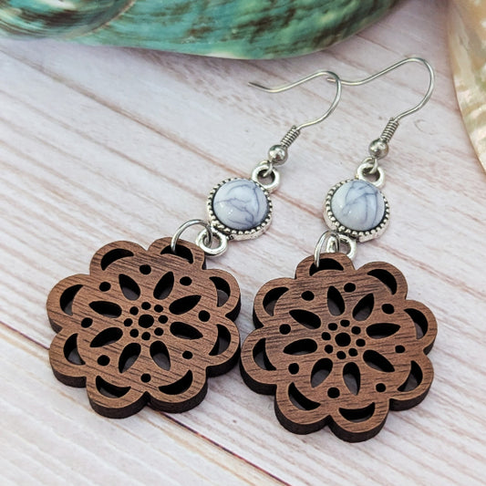 Wooden floral earrings with silver hooks and marbled stones on a light wooden surface.
