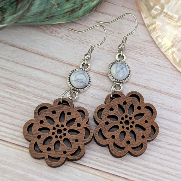 Wooden floral earrings with marble-like stones on a light wooden surface