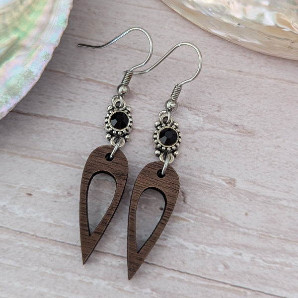 Wooden earrings with black crystal connectors, light wood background. Stainless steel hooks.