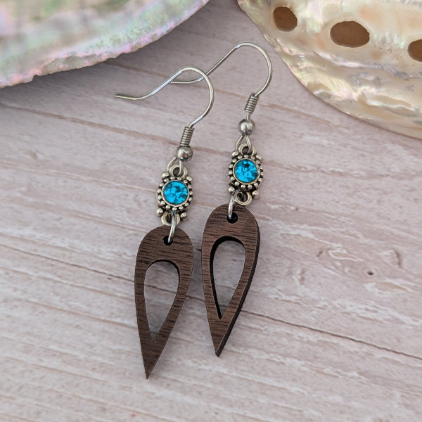 Wooden earrings with blue crystal connectors, light wood background. Stainless steel hooks.