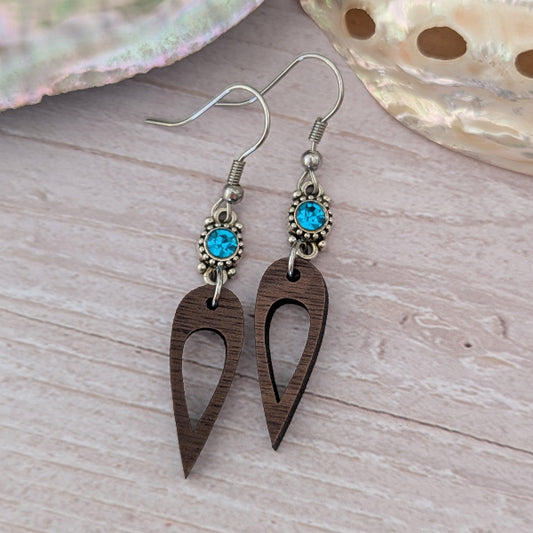 Wooden earrings with blue crystal connectors, light wood background. Stainless steel hooks.
