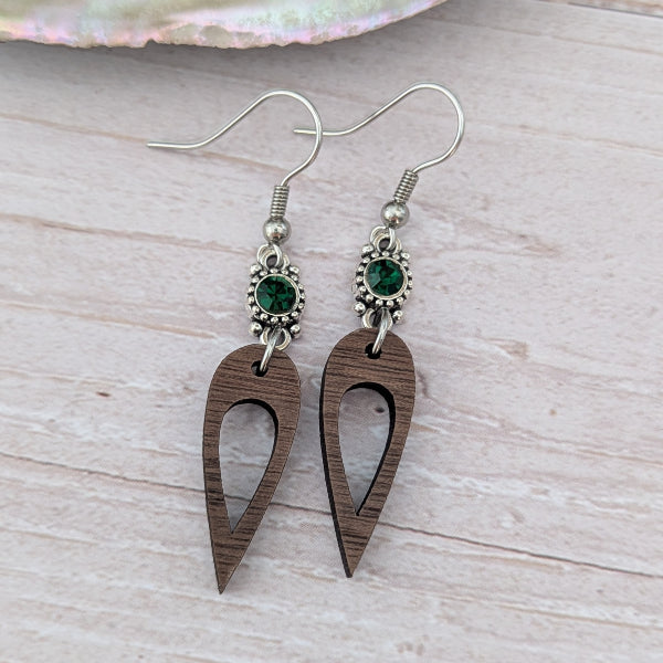 Wooden earrings with green crystal connectors, light wood background. Stainless steel hooks.