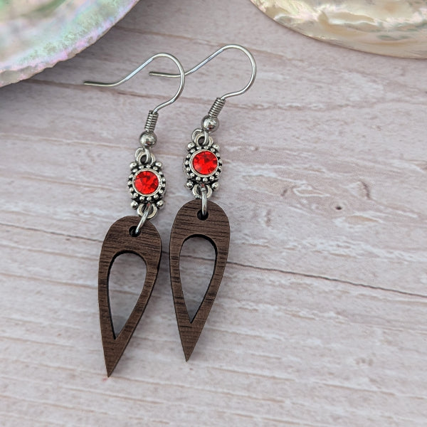 Wooden earrings with red crystal connectors, light wood background. Stainless steel hooks.