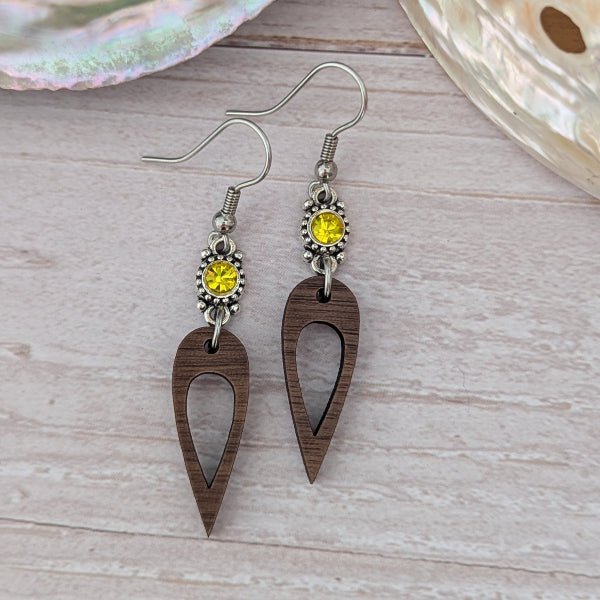Wooden earrings with yellow crystal connectors, light wood background. Stainless steel hooks.