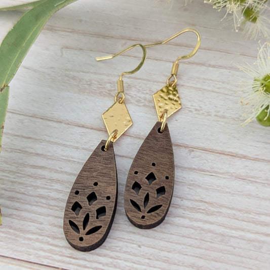 Wooden drop earrings with gold accents on a light wooden surface. Plated gold stainless steel hooks.